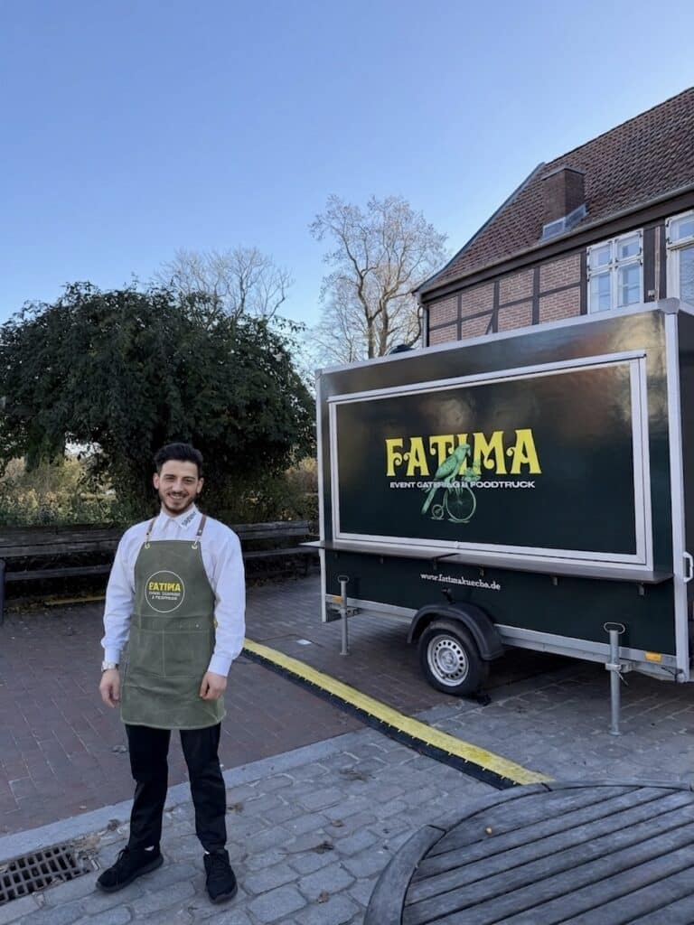 Maged, Inhaber von Fatima Catering, steht im rahmen einer Firmenveranstaltung vor seinem Foodtruck
